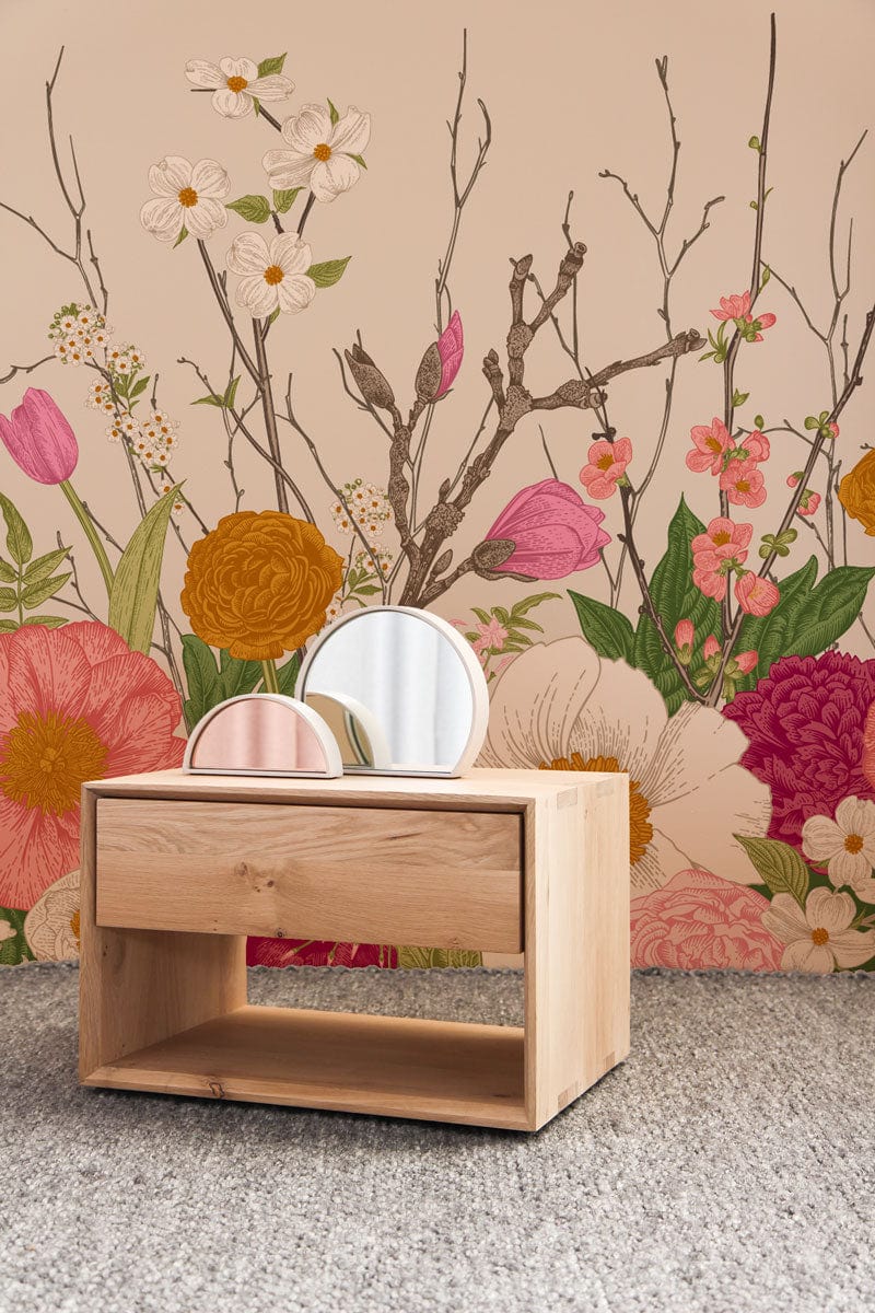 Vibrant floral garden mural wallpaper in room with wooden side table and textured grey carpet.