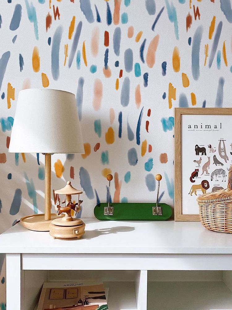 Abstract multicolour brush strokes wallpaper; pastel hues; white desk; table lamp; modern decor.