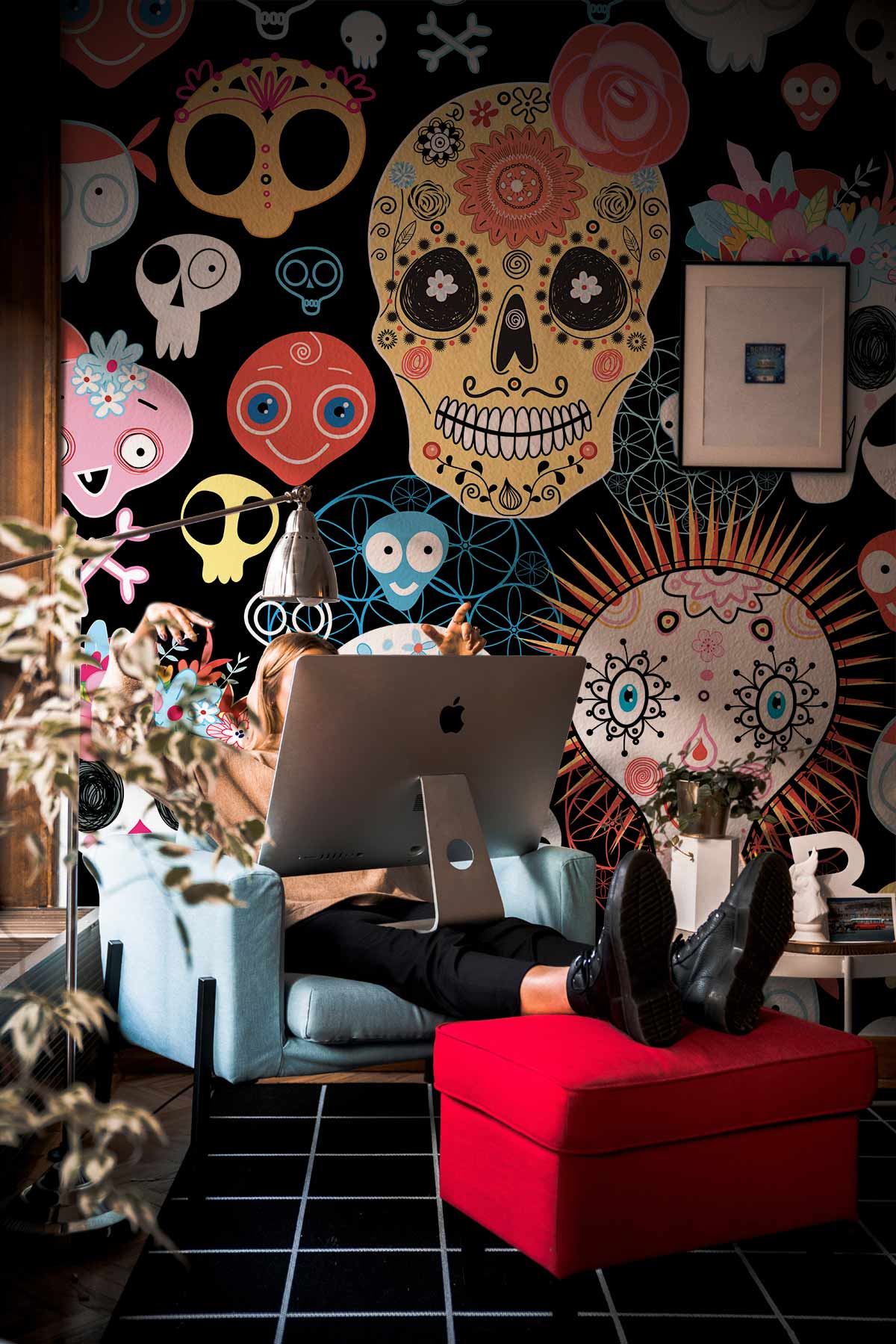 Day of the Dead skull wallpaper, vibrant office decor, blue chair, red footstool, black flooring.