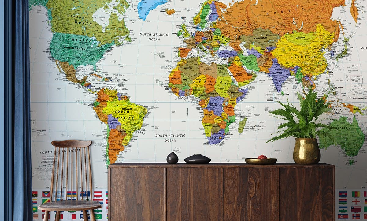Detailed World Map Mural Wallpaper in vibrant colours, wood console, natural chair, blue drapes.