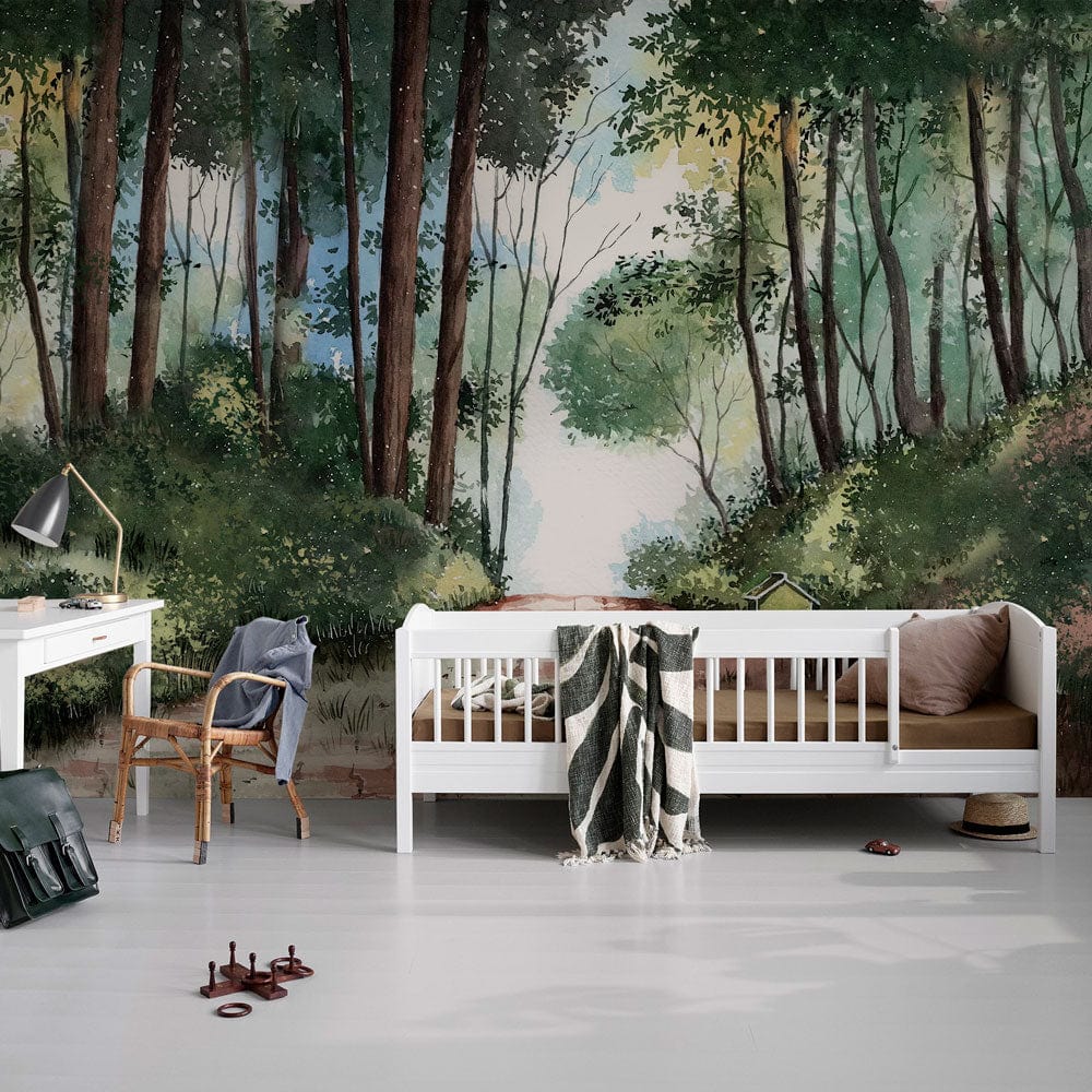 Forest path mural wallpaper in green, brown tones behind white sofa, wooden chair, white desk, light flooring.