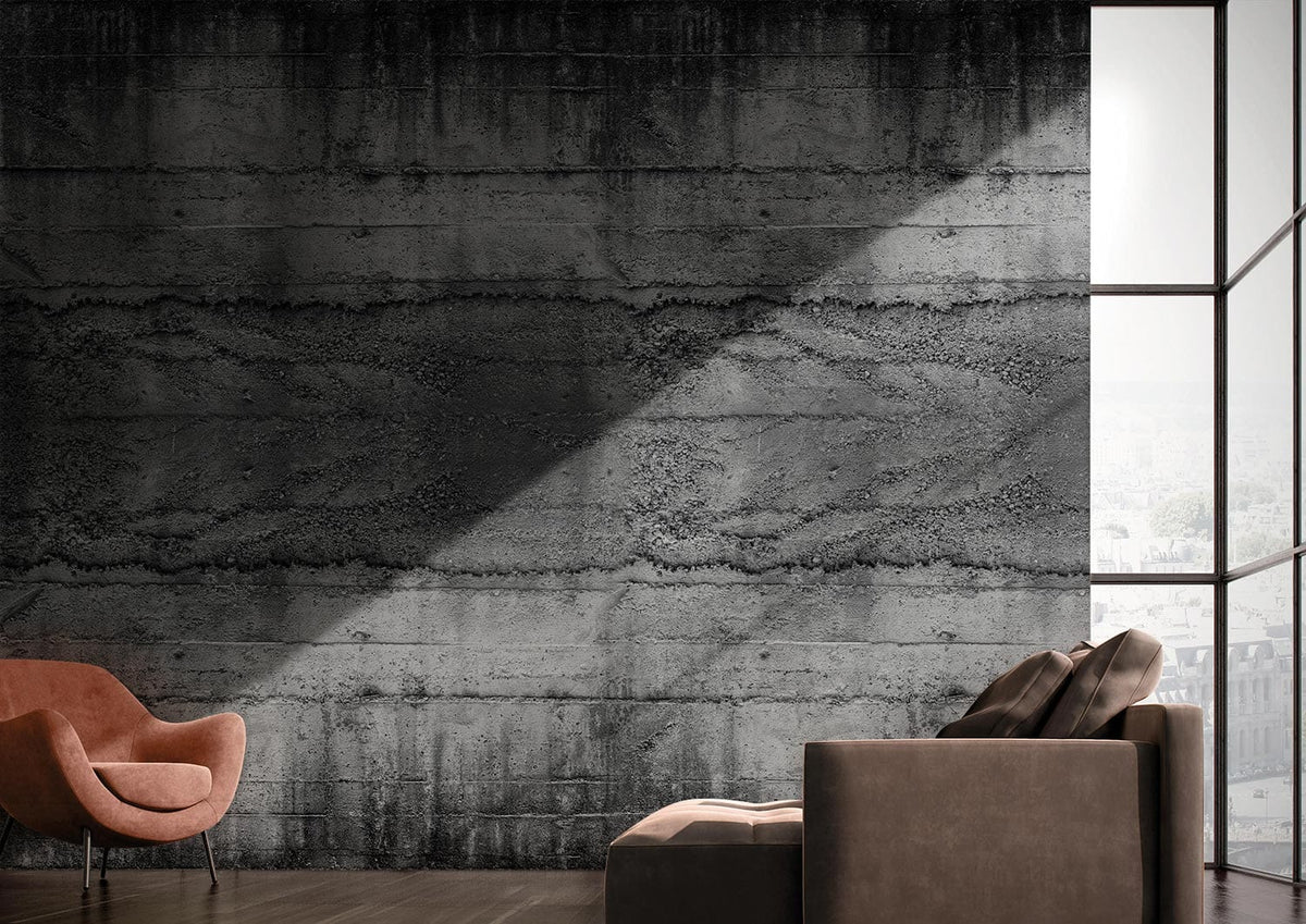 Industrial grey concrete mural wallpaper with brown armchair, grey sofa, and dark wooden flooring in modern interior.