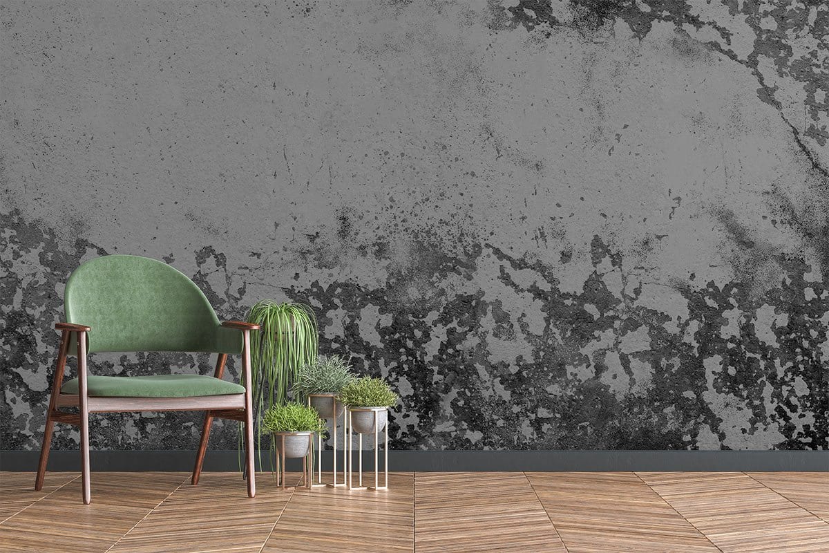 Antique grey distressed mural wallpaper with green armchair, wooden flooring, and industrial chic design.