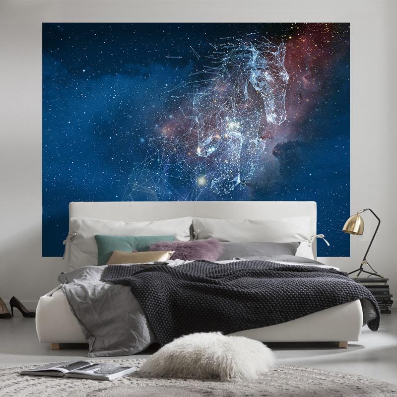 Galactic Constellation Night Sky mural in bedroom, with white bed, Mid-century lamp, cosy grey throw.