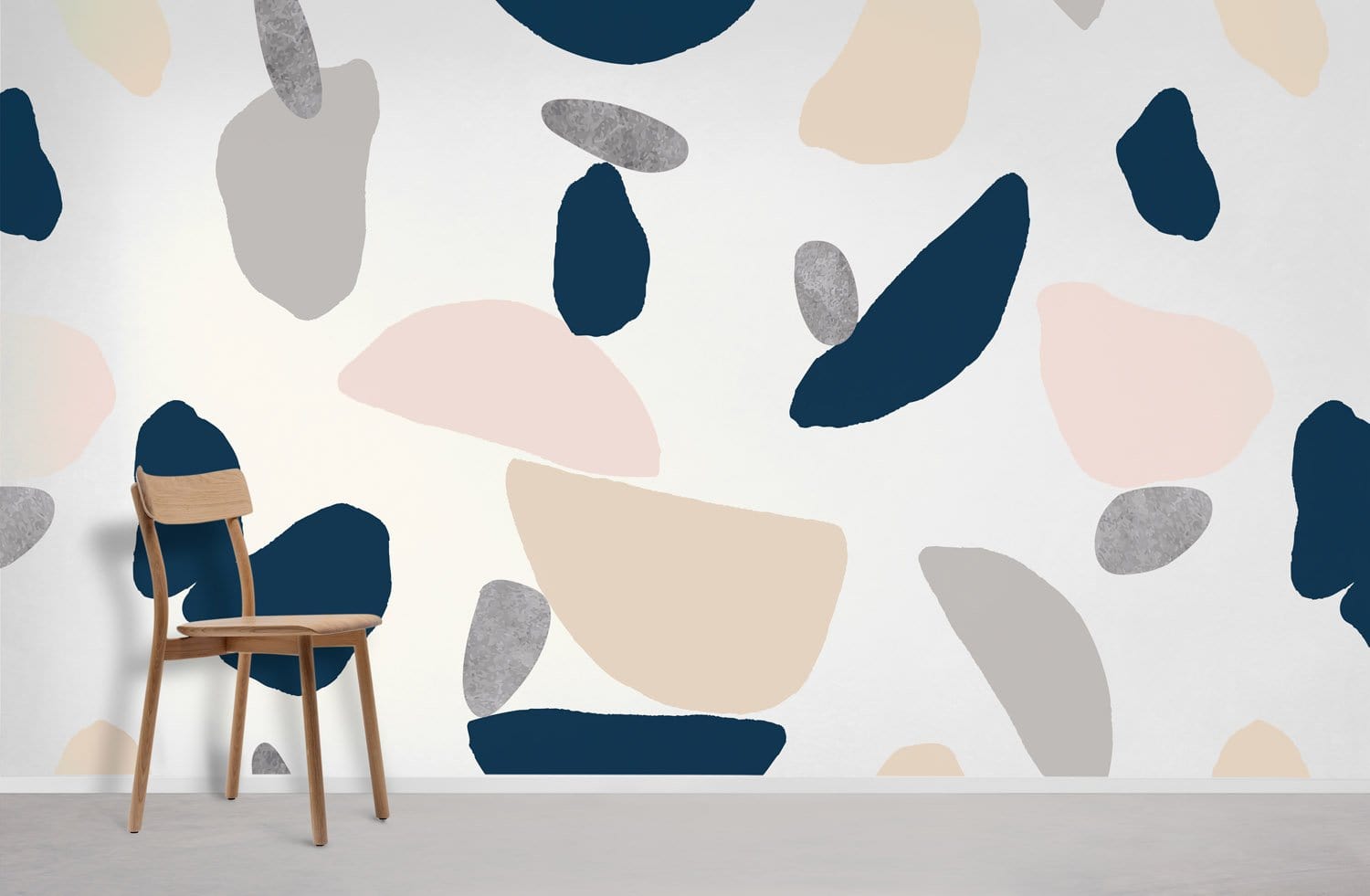 Modern abstract terrazzo wallpaper in navy, beige, blush tones; wooden chair, minimalist decor, grey floor.