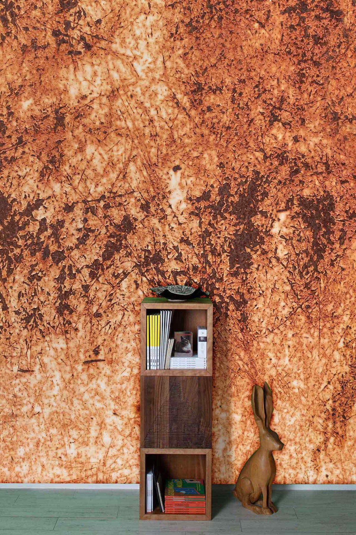 Rustic textured autumnal-orange abstract wallpaper with wood shelf, rabbit decor, light green flooring.