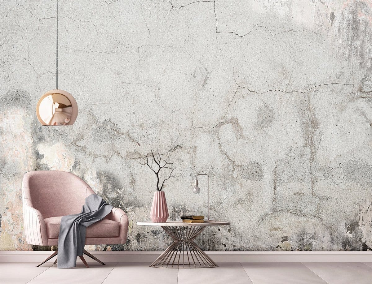 Pink armchair and table against grey vintage industrial concrete effect mural wallpaper in modern living room.