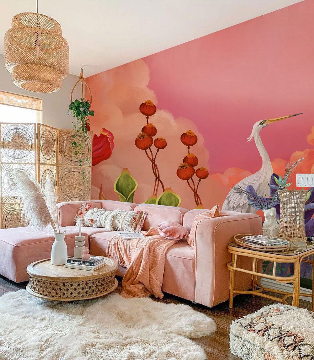 Pink sofa living room with floral heron mural, rattan accents, wooden floor, and pastel sunset wallpaper.