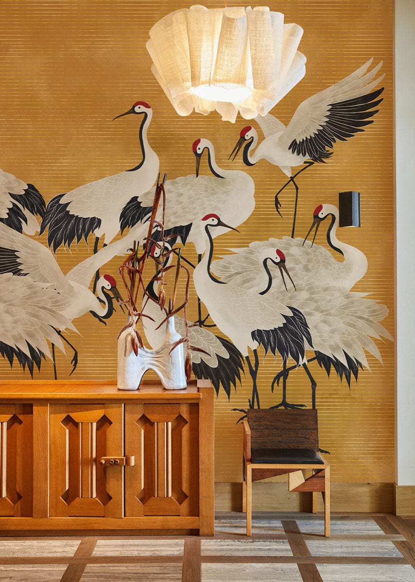 Elegant Golden Crane Mural Wallpaper in stylish room with wood cabinet, chair, and hanging lamp.