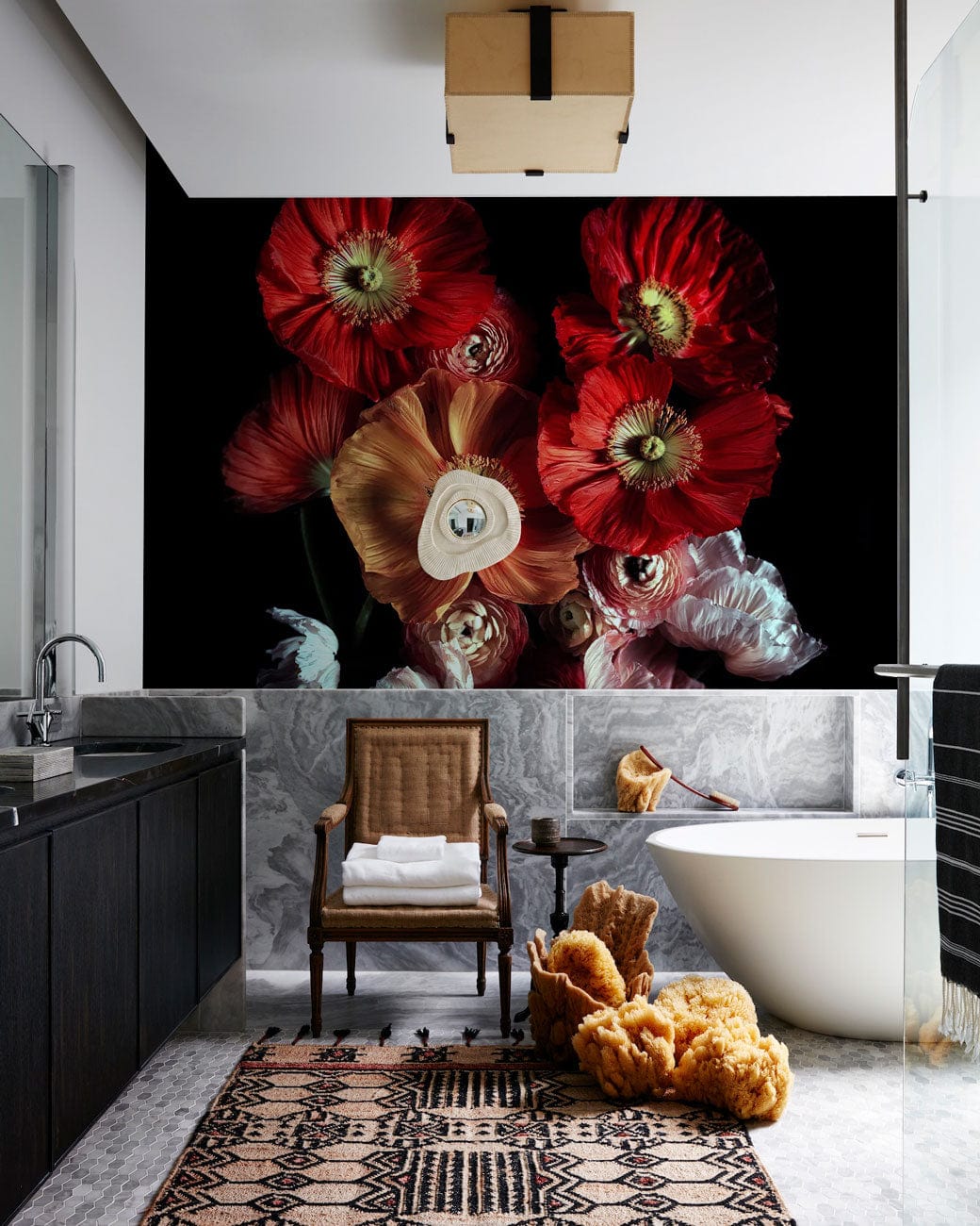 Luxurious bathroom featuring elegant red and white floral wallpaper, modern freestanding bathtub, wooden chair.