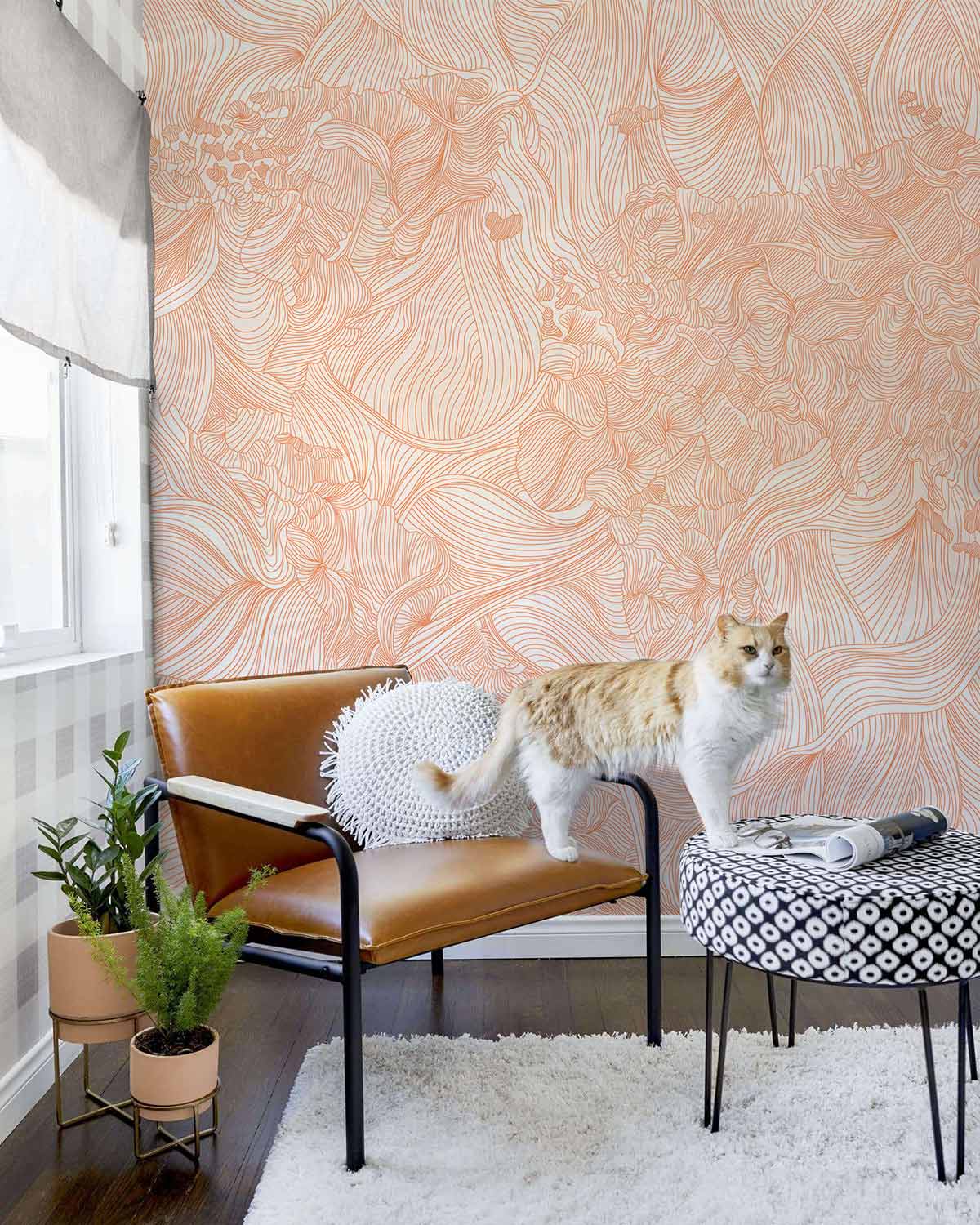 Elegant peach floral swirl wallpaper in living room with leather chair, patterned table, and white rug.