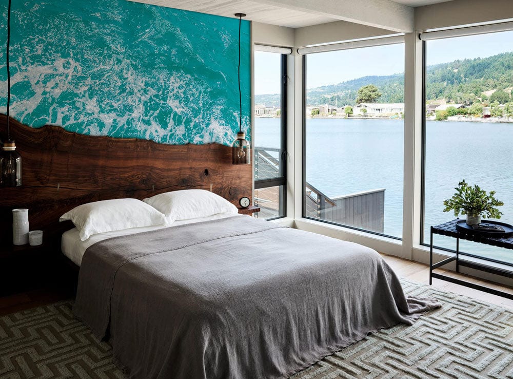 Coastal Serenity bedroom with Turquoise Ocean Waves wallpaper, rustic bed, geometric rug, and ocean view.