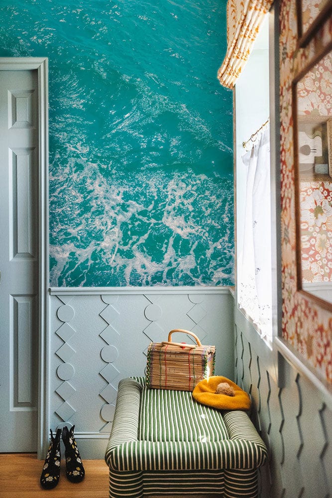 Turquoise Ocean Waves Mural Wallpaper in hallway with green-striped bench, light wood flooring, decorative wall.