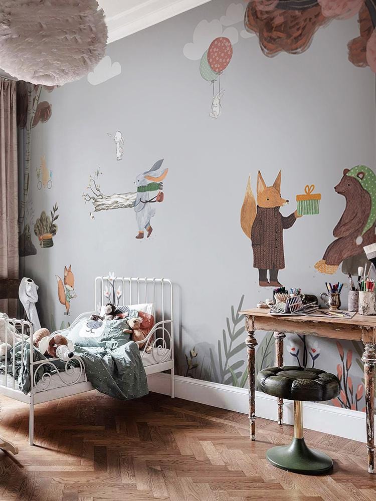Whimsical woodland mural wallpaper in pastel hues, children's bedroom, wooden flooring, white bed, desk.