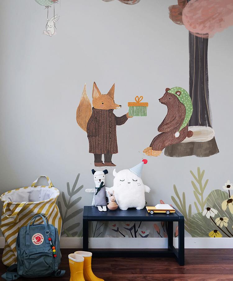 Whimsical woodland creatures mural wallpaper with pastel tones, children's room decor; hardwood floor, toy bench.