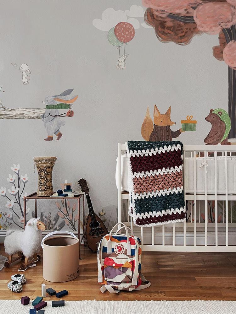 Whimsical Woodland Creatures mural wallpaper in pastel hues, nursery crib, wooden flooring, playful decor.