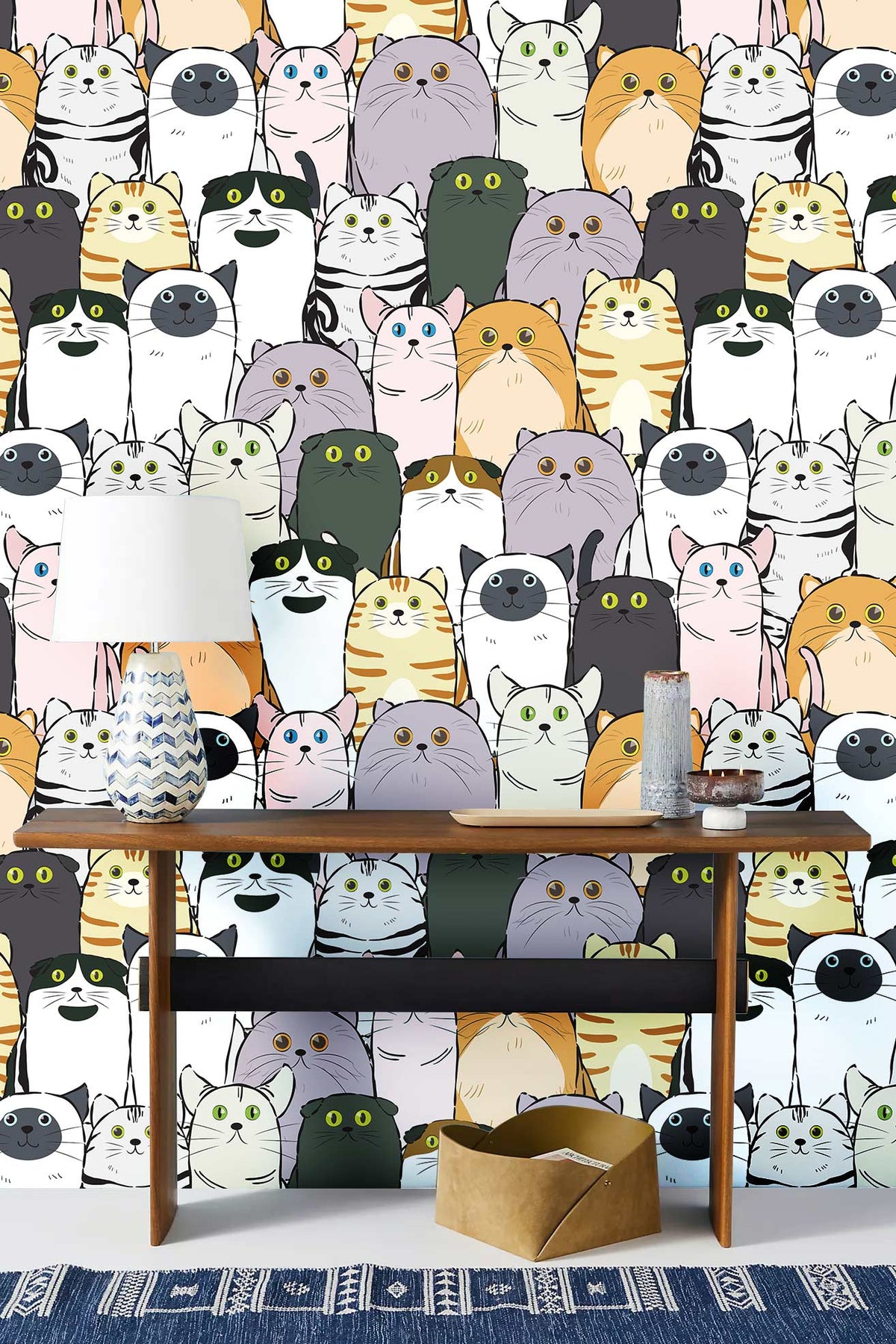 Adorable multicolour cartoon cat wallpaper in crafting room with wooden table and patterned blue rug.