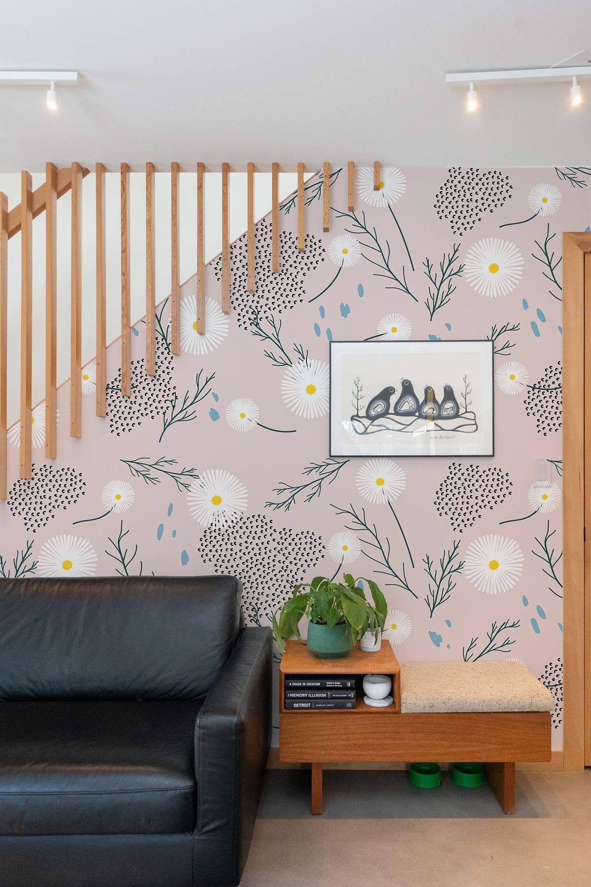 Botanical Bliss floral wallpaper, black leather sofa, wooden furniture, framed art, modern living room design.