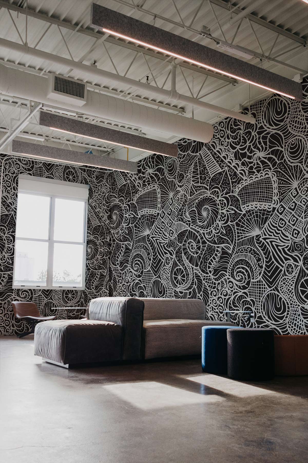 Intricate black and white abstract wallpaper in modern loft, grey sofa, concrete floor, contemporary design.