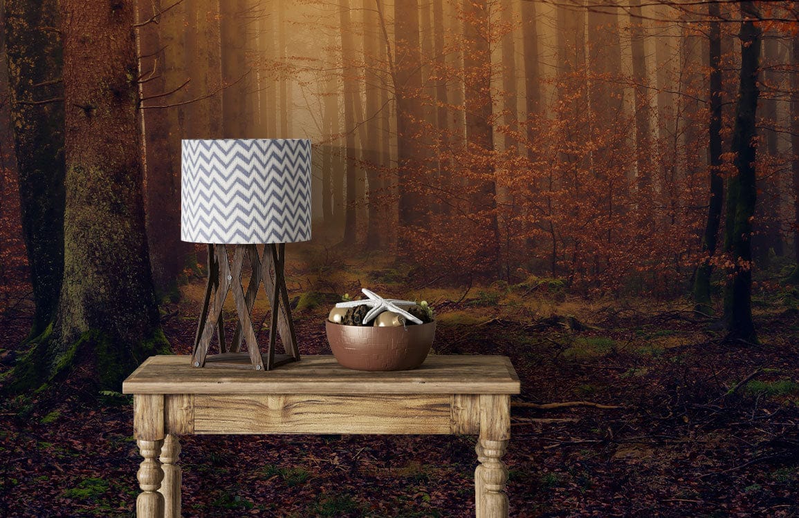 Enchanted forest mural wallpaper, earthy tones; wooden table, chevron lamp in cosy room setting.