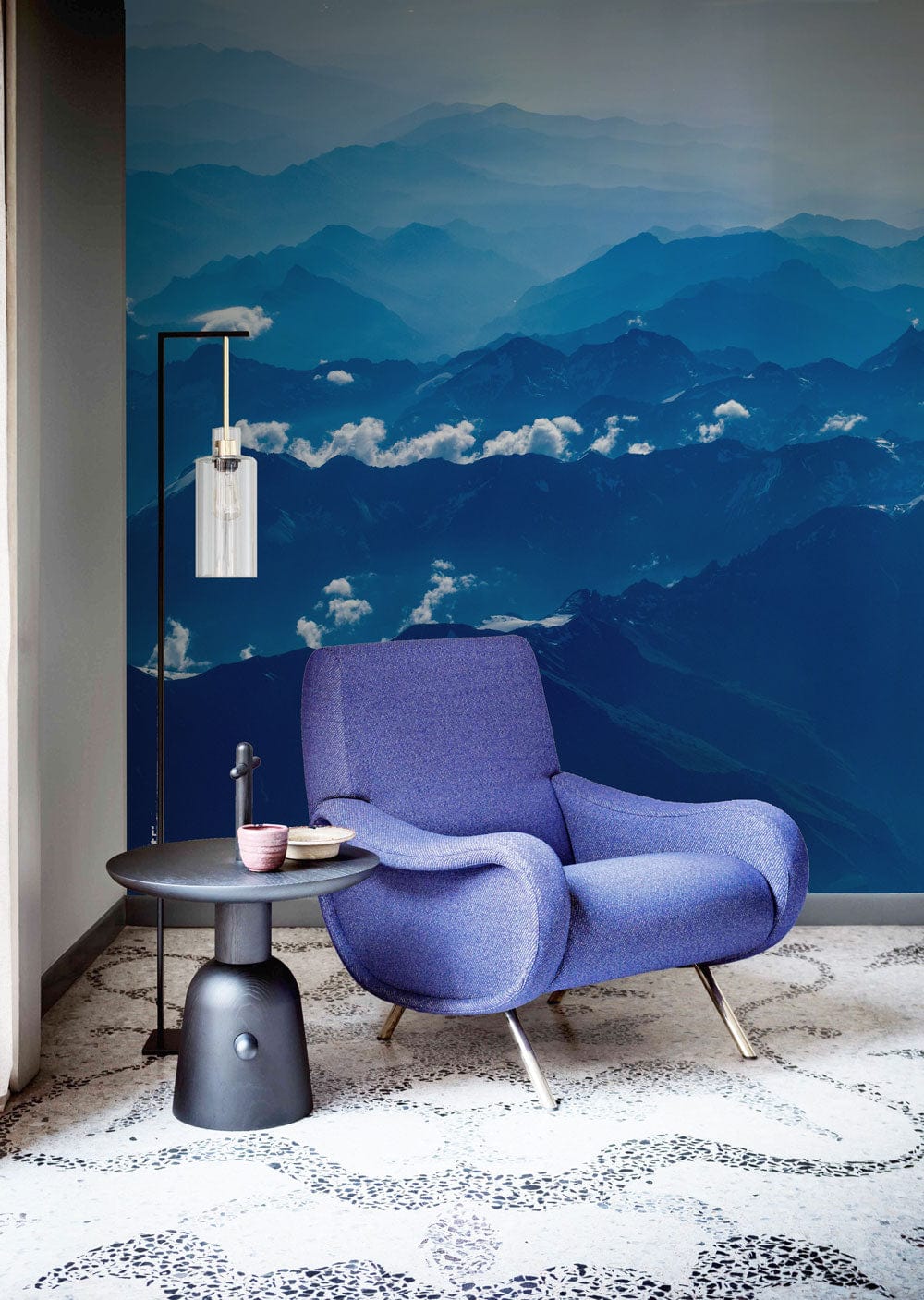 Blue mountain mural wallpaper with blue armchair, modern lamp, and patterned flooring in living room.