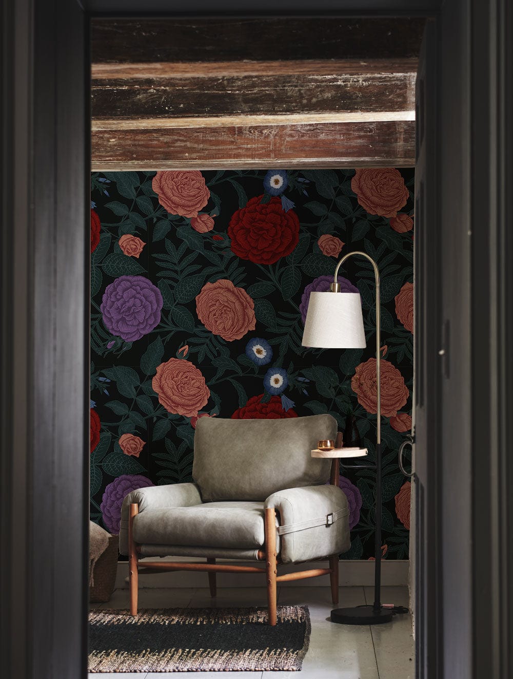 Vintage floral wallpaper, rich blooms, cosy armchair, floor lamp, wooden beam ceiling, rug flooring.