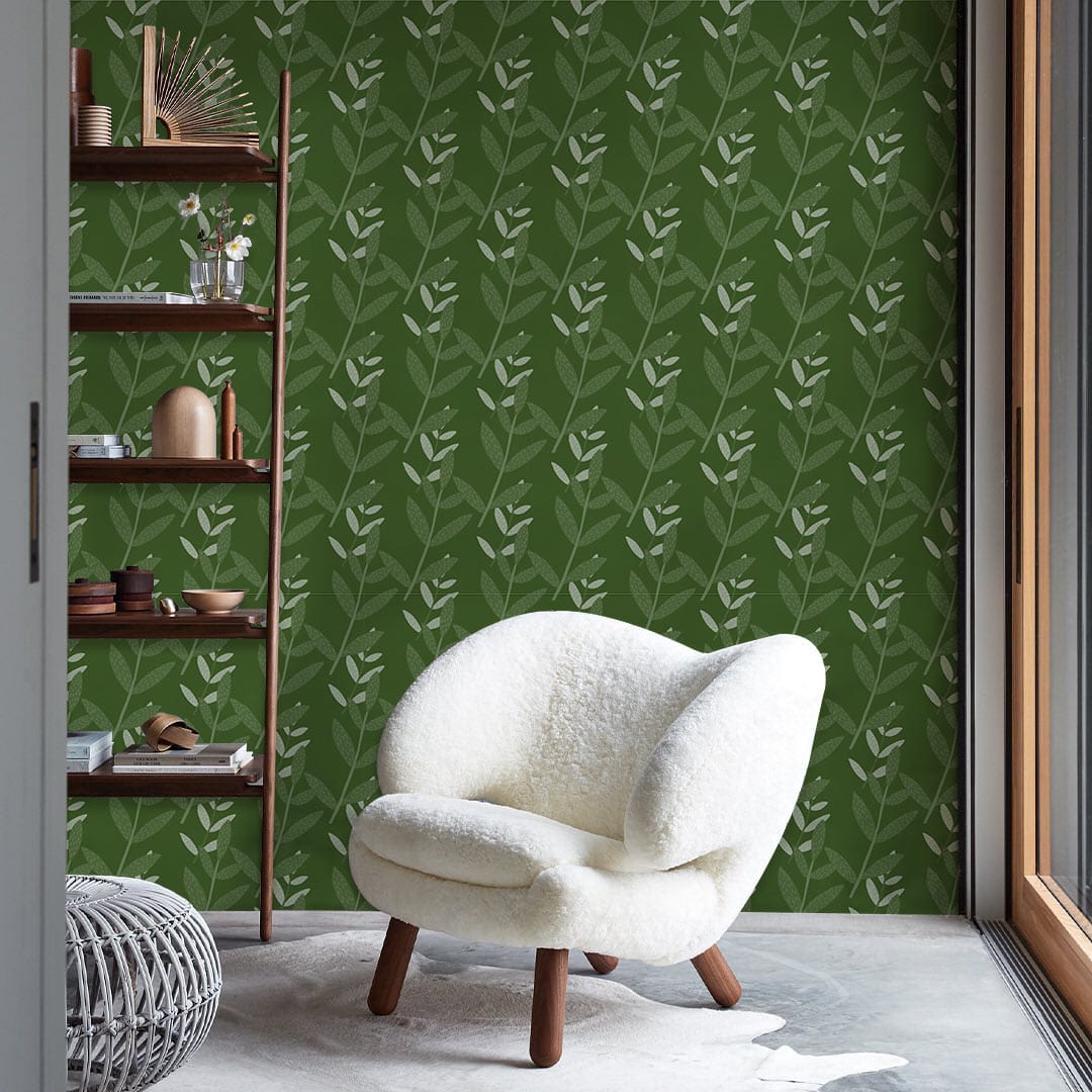 Elegant green botanical wallpaper, cosy white armchair, wooden shelving, modern room design, concrete flooring.