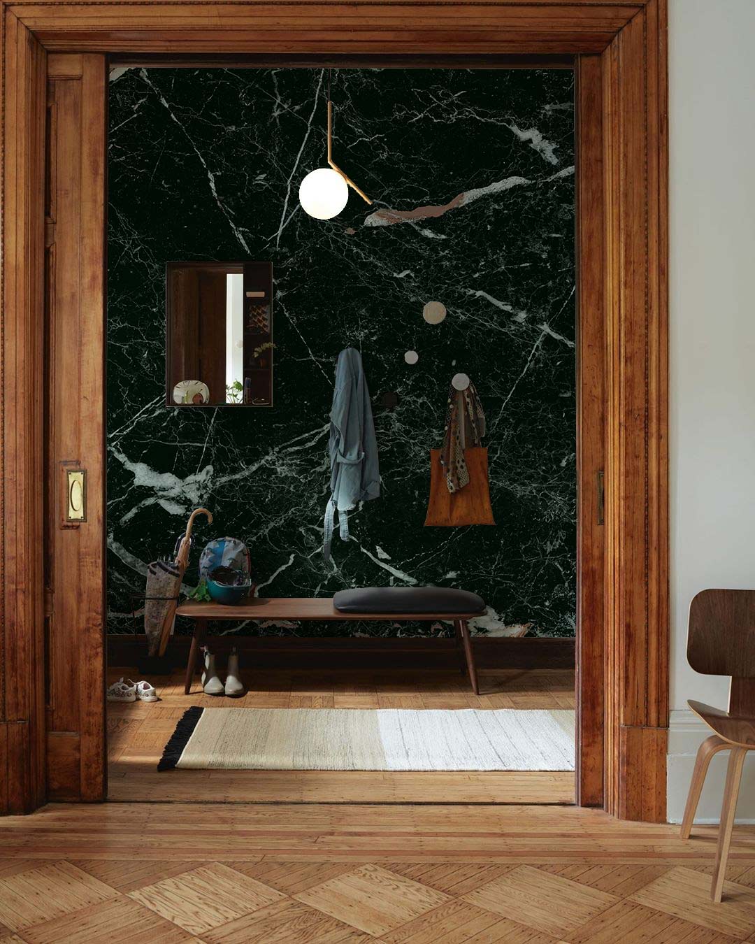 Elegant black marble effect wallpaper with white veining, wooden borders, bench, parquet flooring in hallway.
