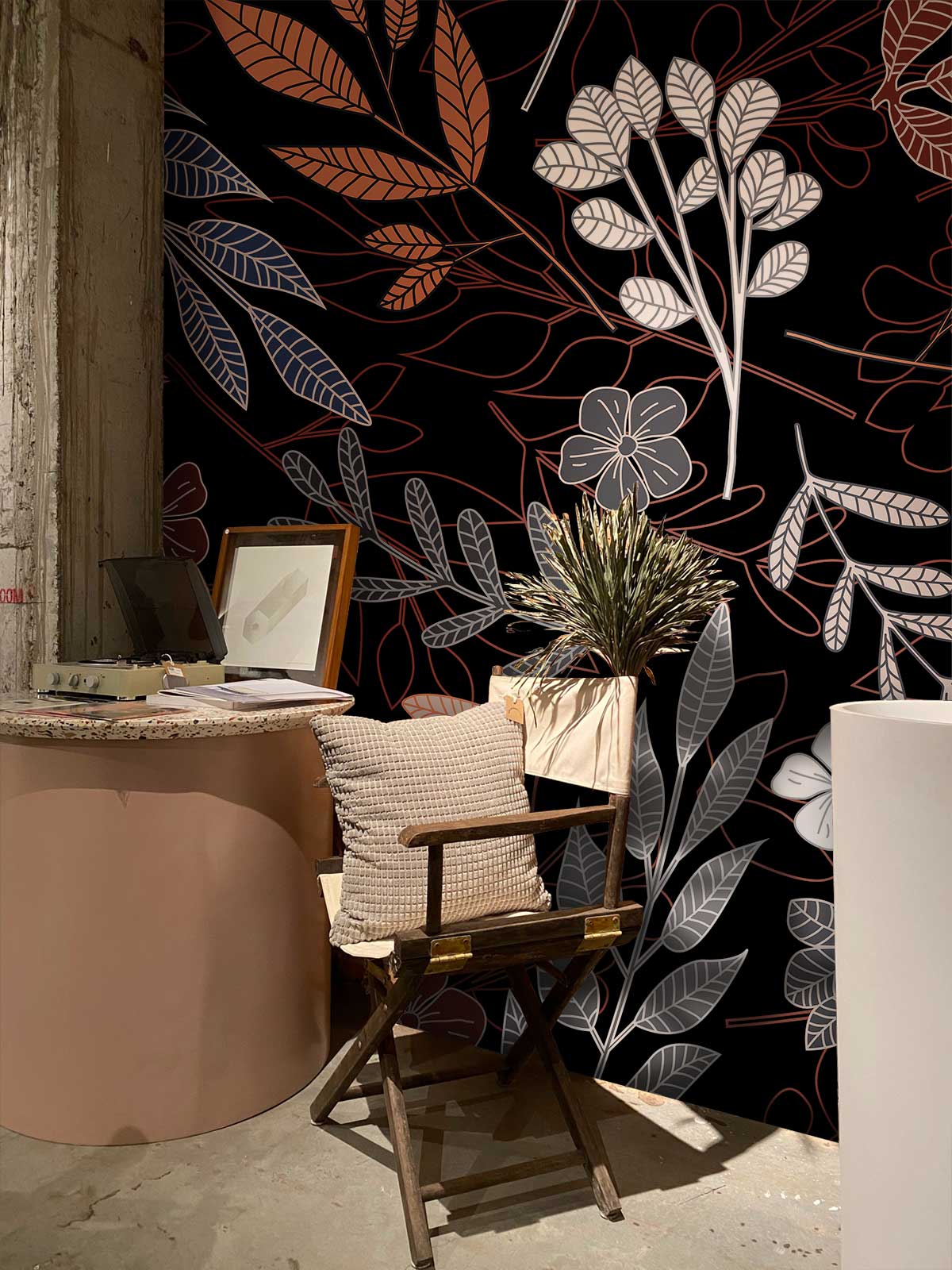 Elegant Floral Botanical Wallpaper in black with rustic chair, round desk, and industrial-style wall.