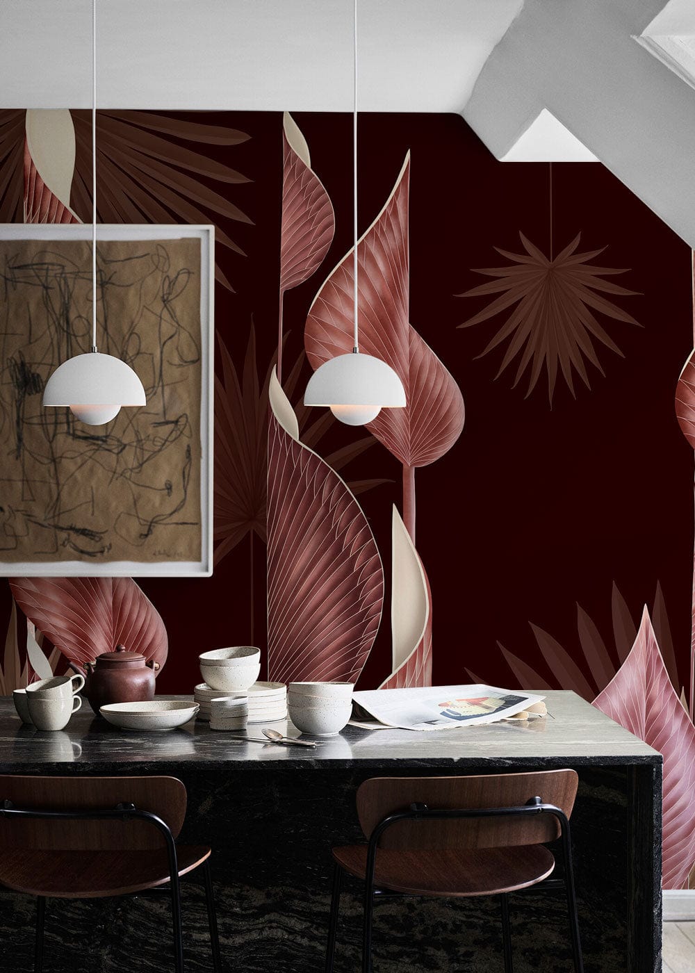 Floral botanical dark red-pink wallpaper with leaf pattern, framed art, pendant lights, black dining table.