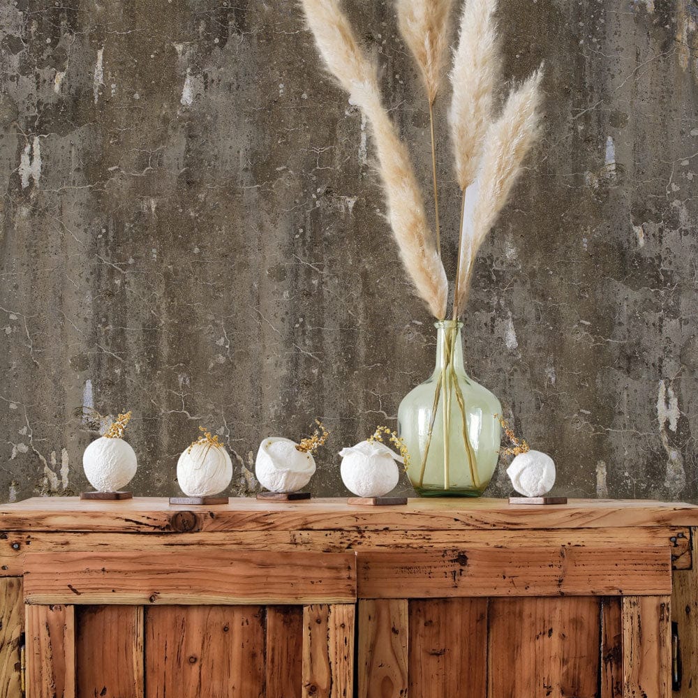 Vintage industrial wallpaper with earthy tones, distressed texture, wooden table, vase with pampas grass.