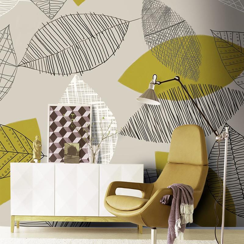Autumnal leaf pattern beige and green mural wallpaper with mustard chair and white sideboard in living room.