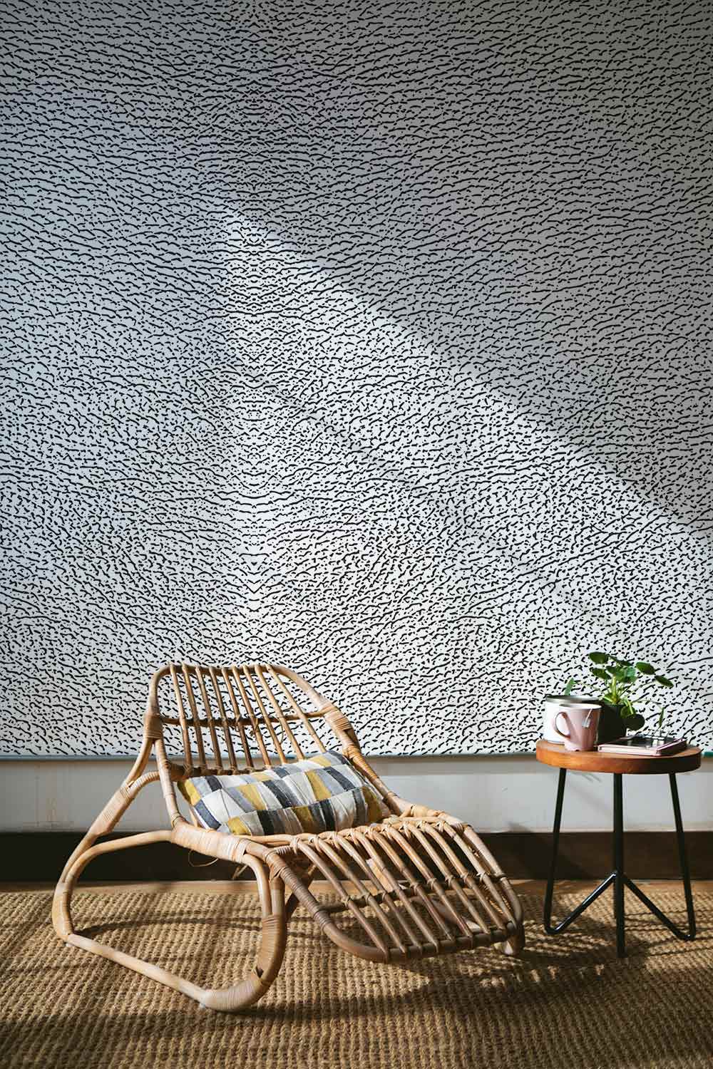 Elegant textured grey leather-look wallpaper mural, rattan chair, cosy living room with woven carpet flooring.