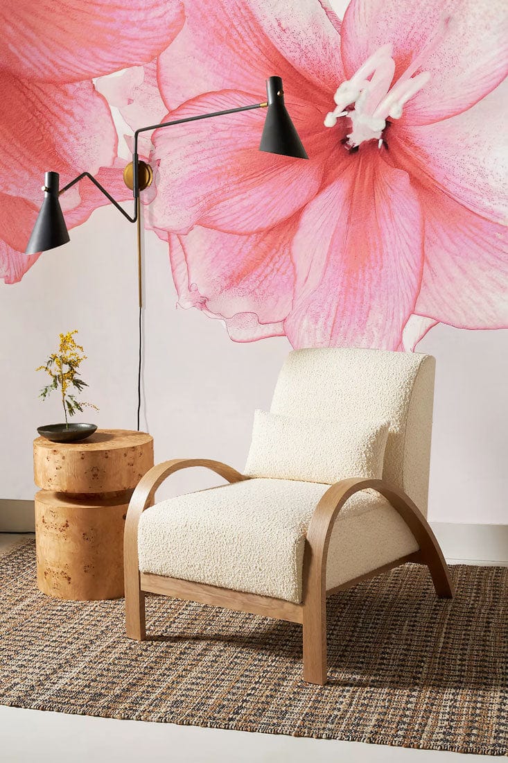 Elegant pink floral wall mural, beige armchair, wooden side table, black lamp, woven rug, modern decor.