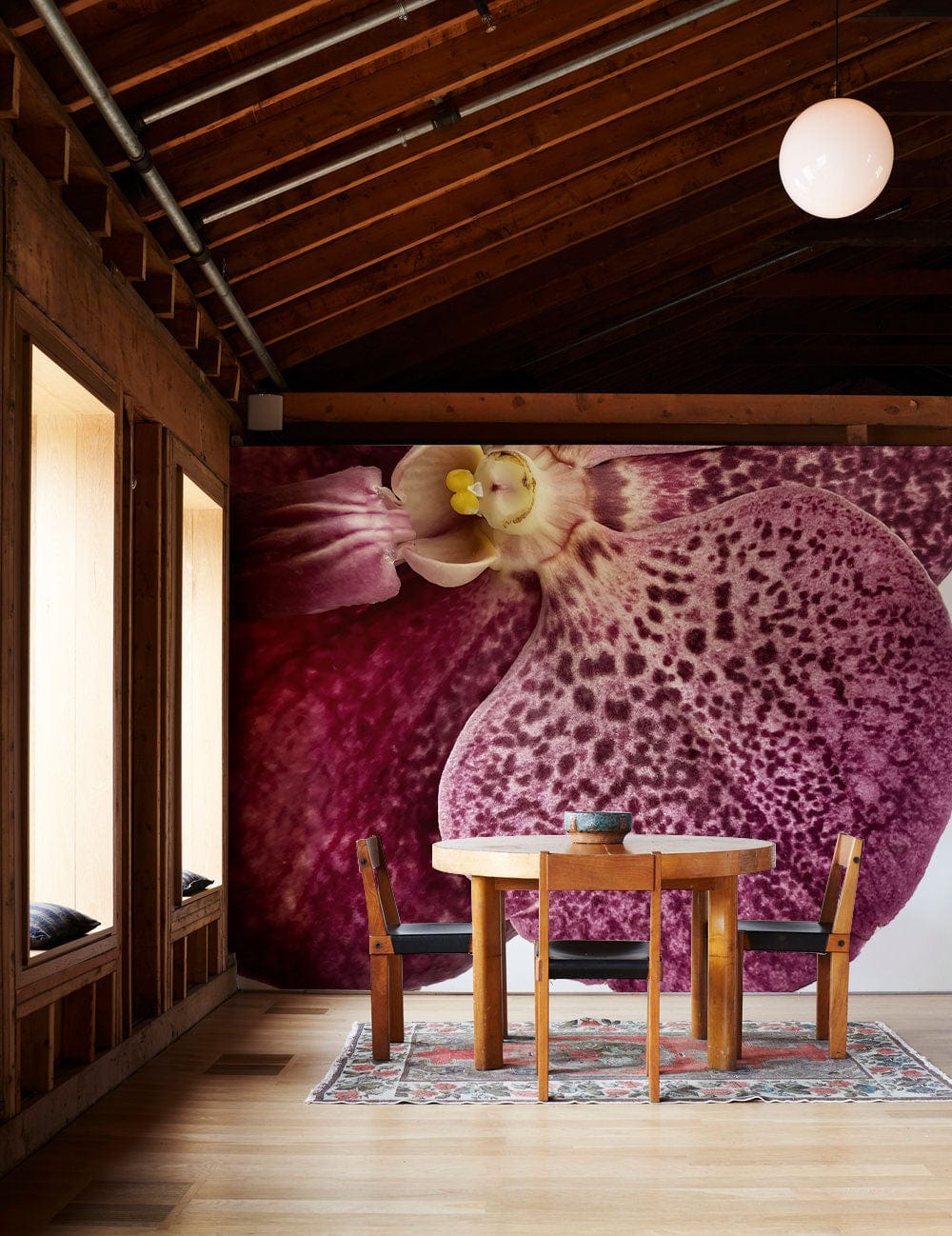Orchid Elegance wallpaper in dining room with wooden ceiling, table, chairs, rug, and floor. Luxurious decor.