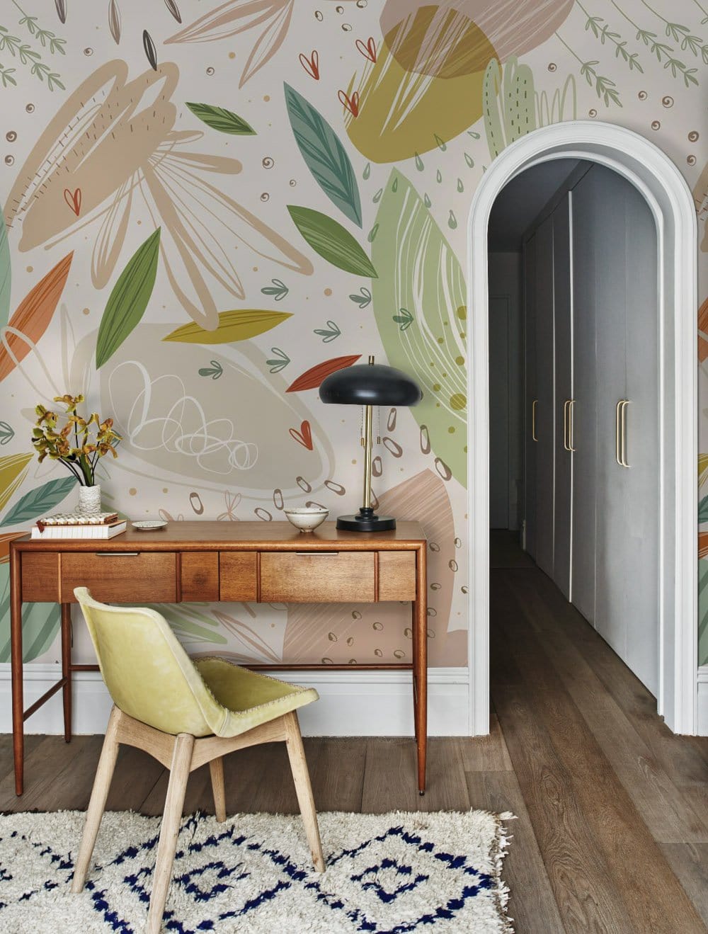 Abstract botanical wallpaper with wooden desk, chair, and rug in modern hallway with earthy tones.