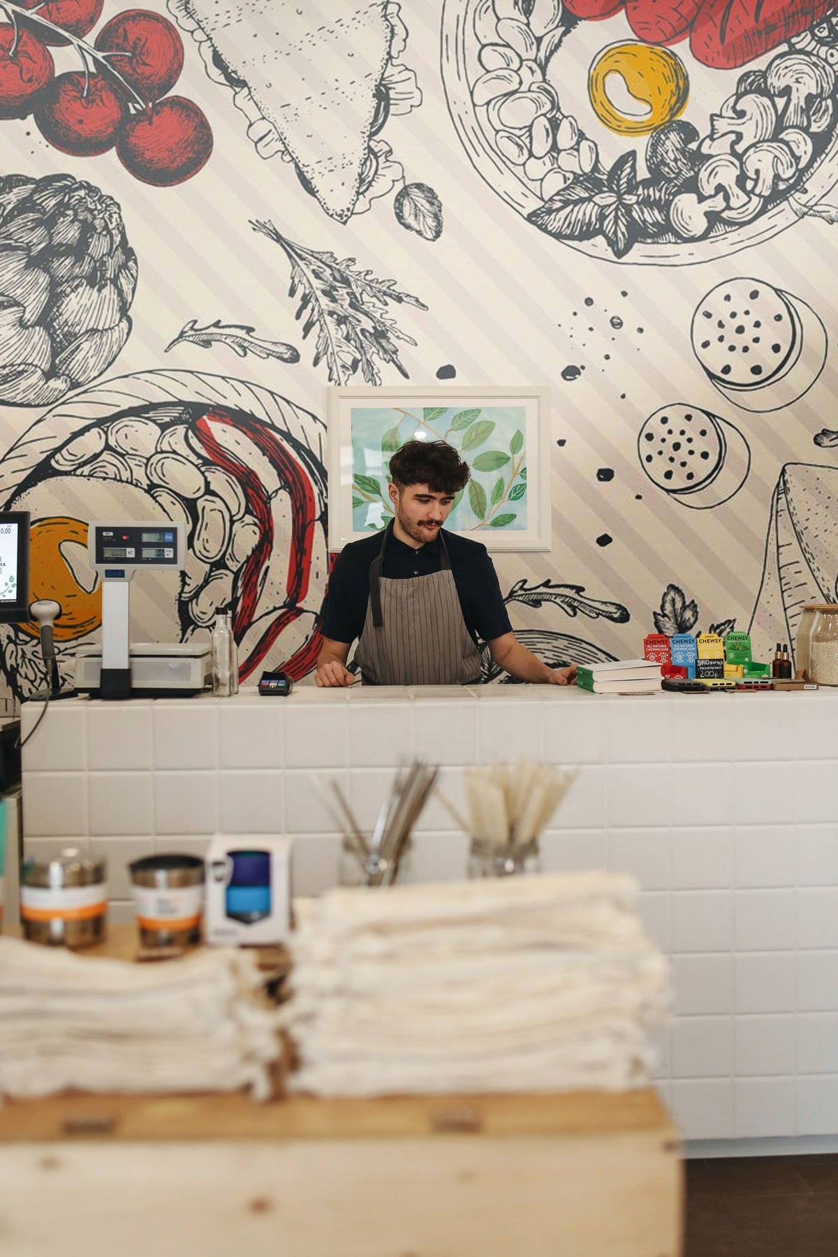 Gourmet Feast Sketch Wallpaper adds flair to white countertop in kitchen setting, red accents visible.