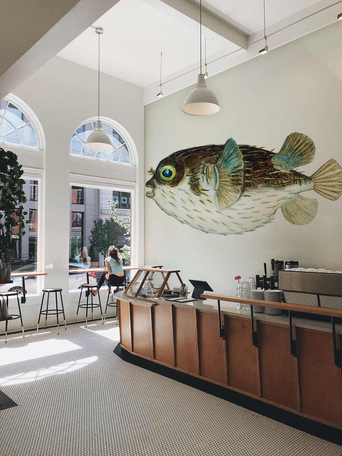 Cafe adorned with Vintage Nautical Pufferfish Wallpaper, featuring soft blues and browns, tiled flooring.