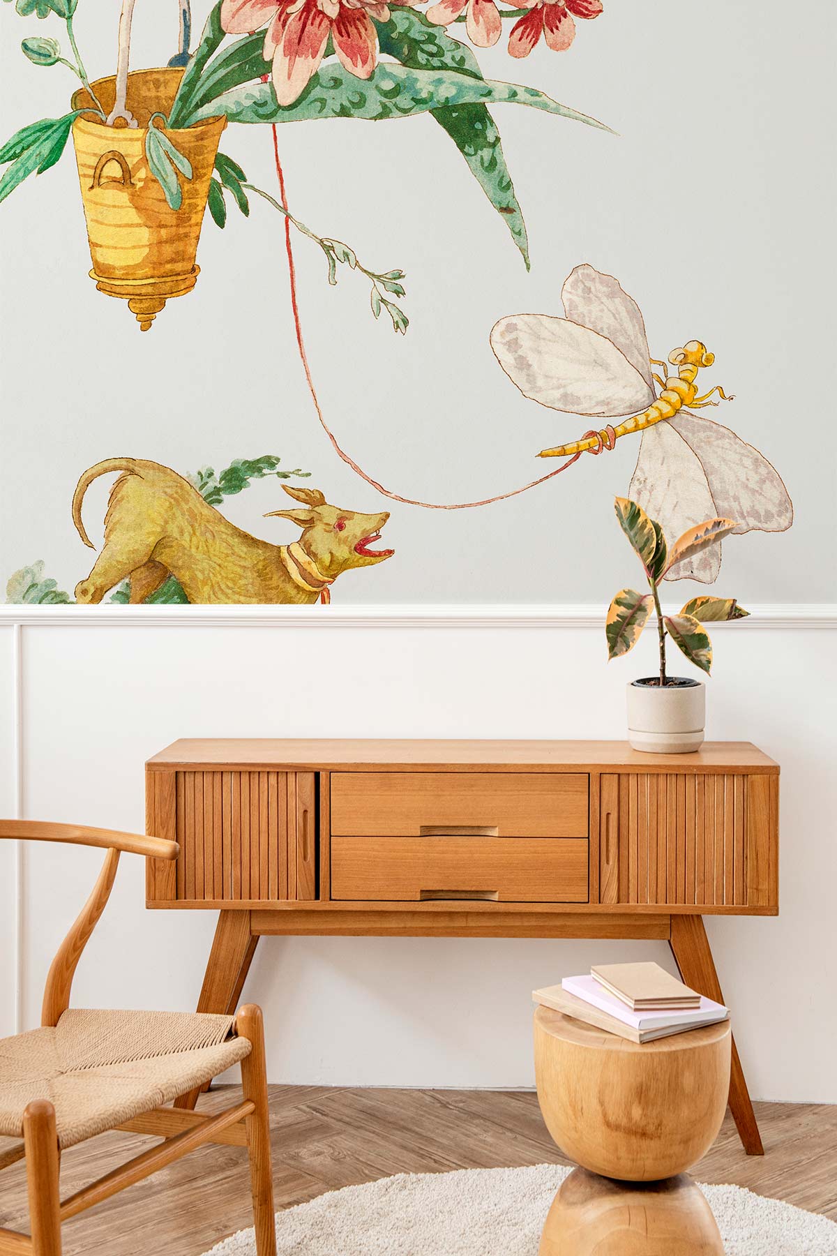 Vintage Whimsical Dog and Dragonfly mural in soft hues with wooden sideboard; mid-century chair nearby.