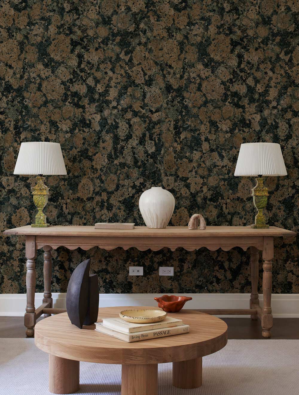 Vintage granite look wallpaper in earthy tones, wooden table, beige carpet, round coffee table, vases.