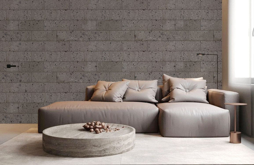 Grey brick wallpaper in living room; modern taupe sofa; stone coffee table; industrial style.