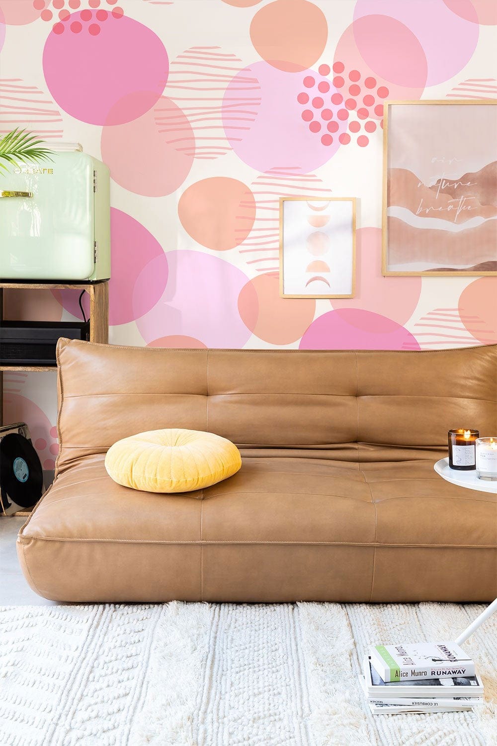 Playful pink and peach polka dot wallpaper, brown leather sofa, modern art decor, stylish interior.