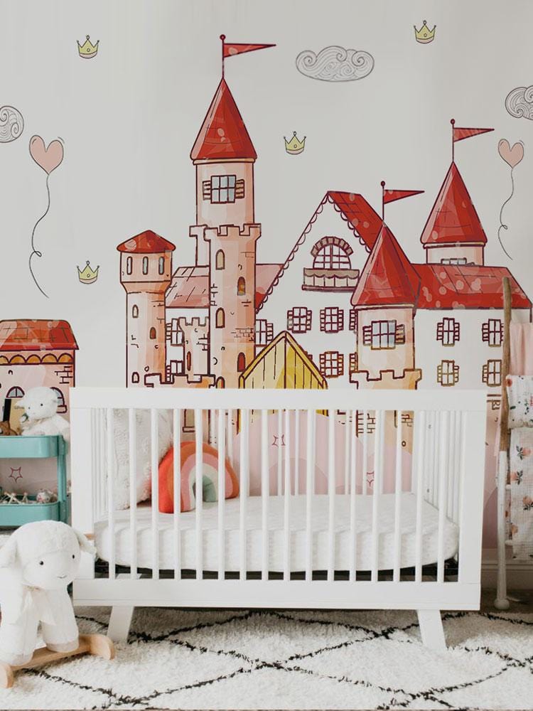 Whimsical pink castle mural wallpaper in children's room, white crib, plush rug, charming decor elements.