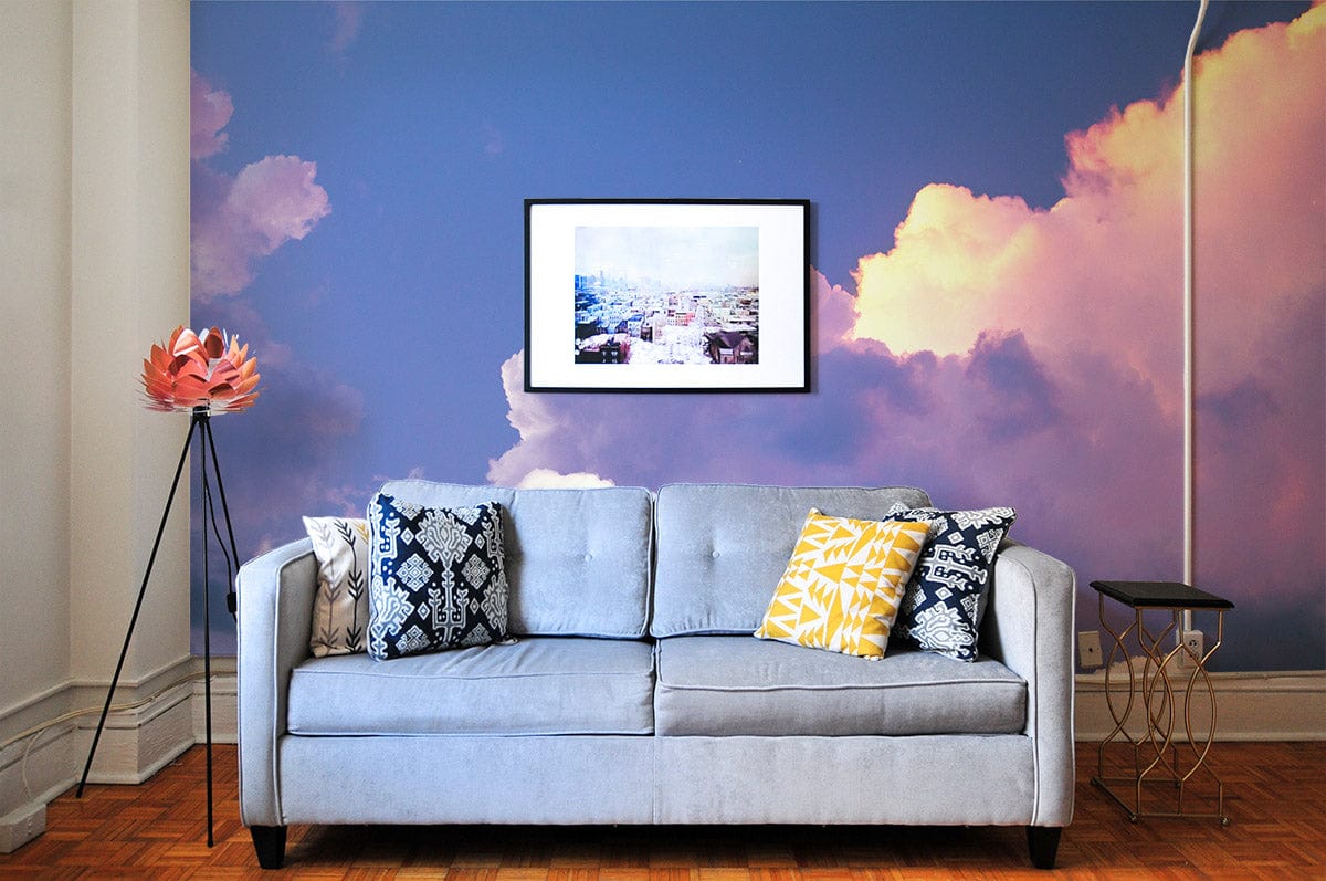 Dreamy Pastel Cloudscape Mural Wallpaper, light grey sofa, parquet flooring, framed art, modern living room.