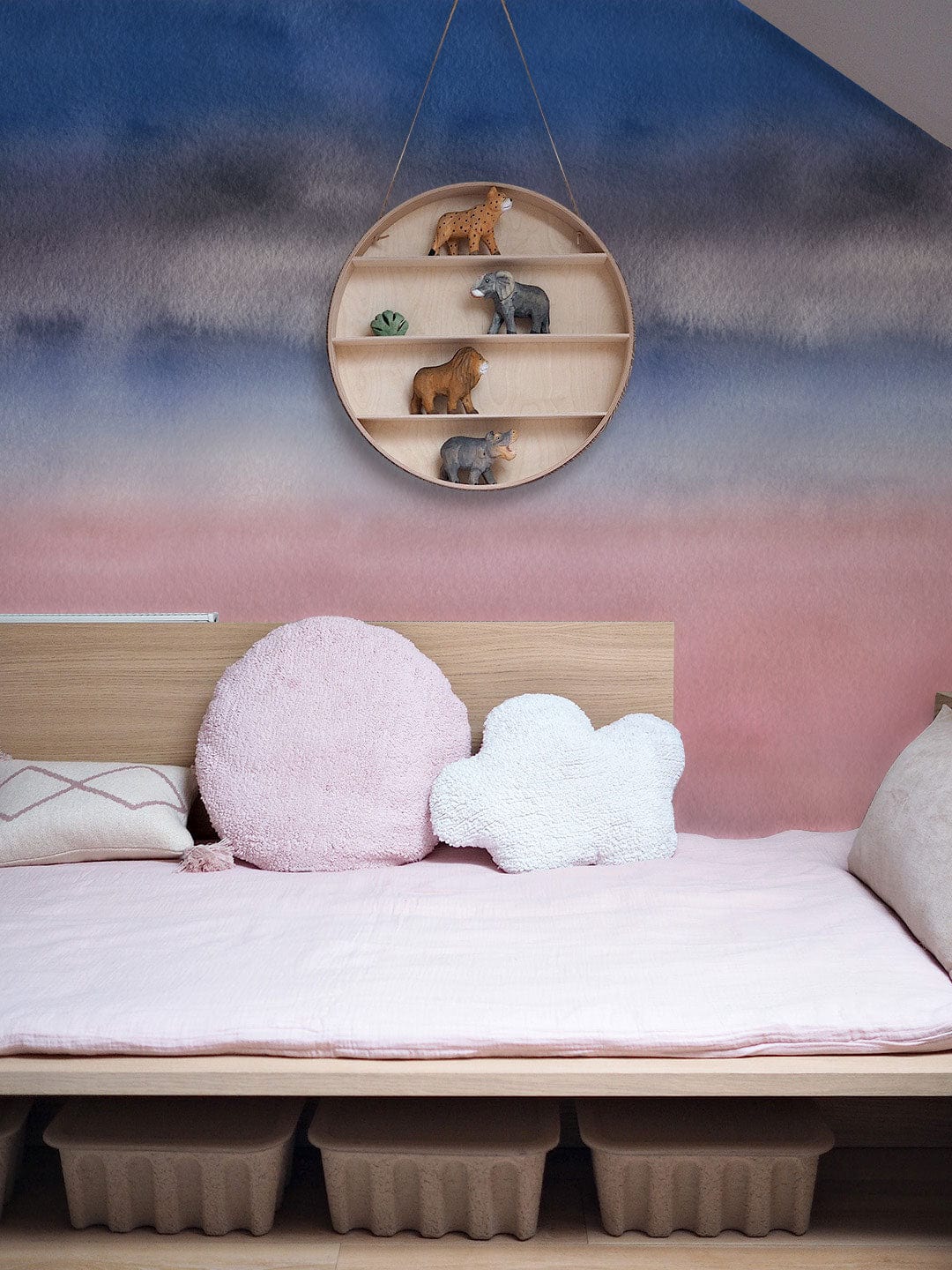 Pastel children's bedroom with Serene Watercolour Horizon Mural, wooden bed, and plush cushions.