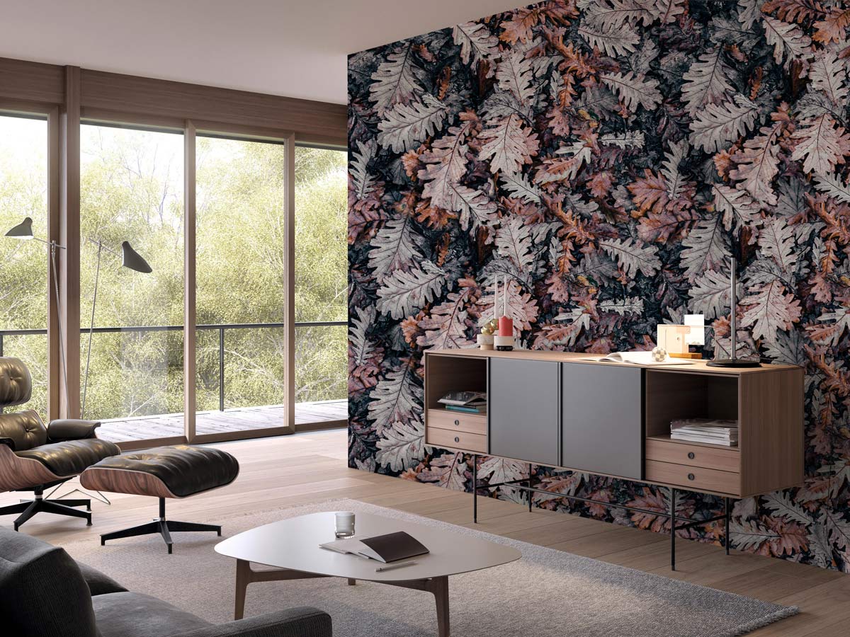 Autumn forest leaf wallpaper in earthy tones; mid-century sideboard, modern lounge chair, rug flooring.