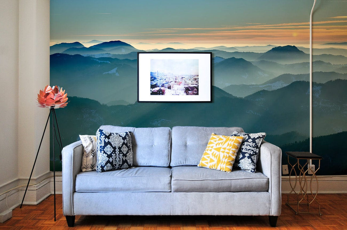Light blue sofa with patterned cushions, parquet flooring, against Serene Mountain Ridge Mist Sunset Wallpaper.