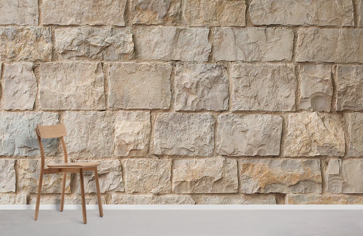 Rustic beige stone brick mural wallpaper with wooden chair, creating natural charm and earthy ambiance.