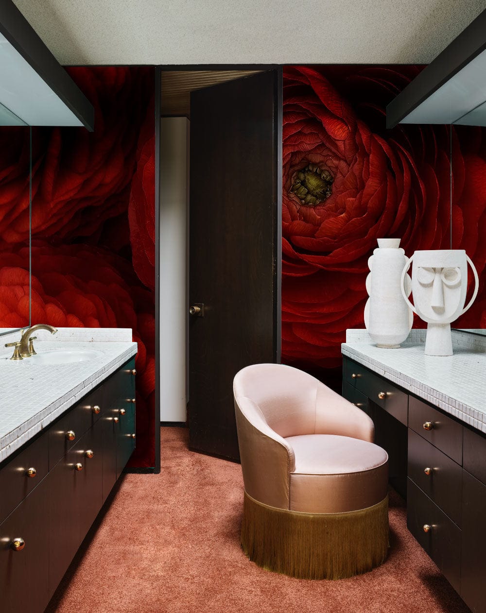 Luxurious red floral mural wallpaper in bathroom, featuring dark cabinets, pink chair, and bronze fixtures.