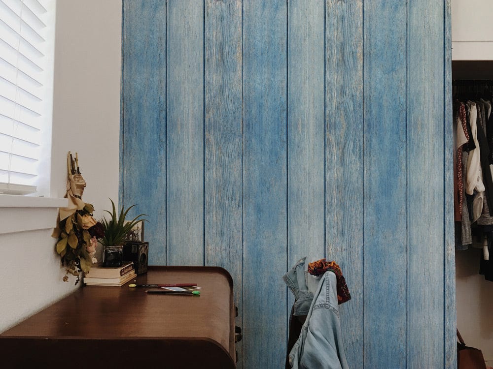 Vintage blue wooden plank wallpaper, coastal interior design, brown desk, casual chair, white wall.